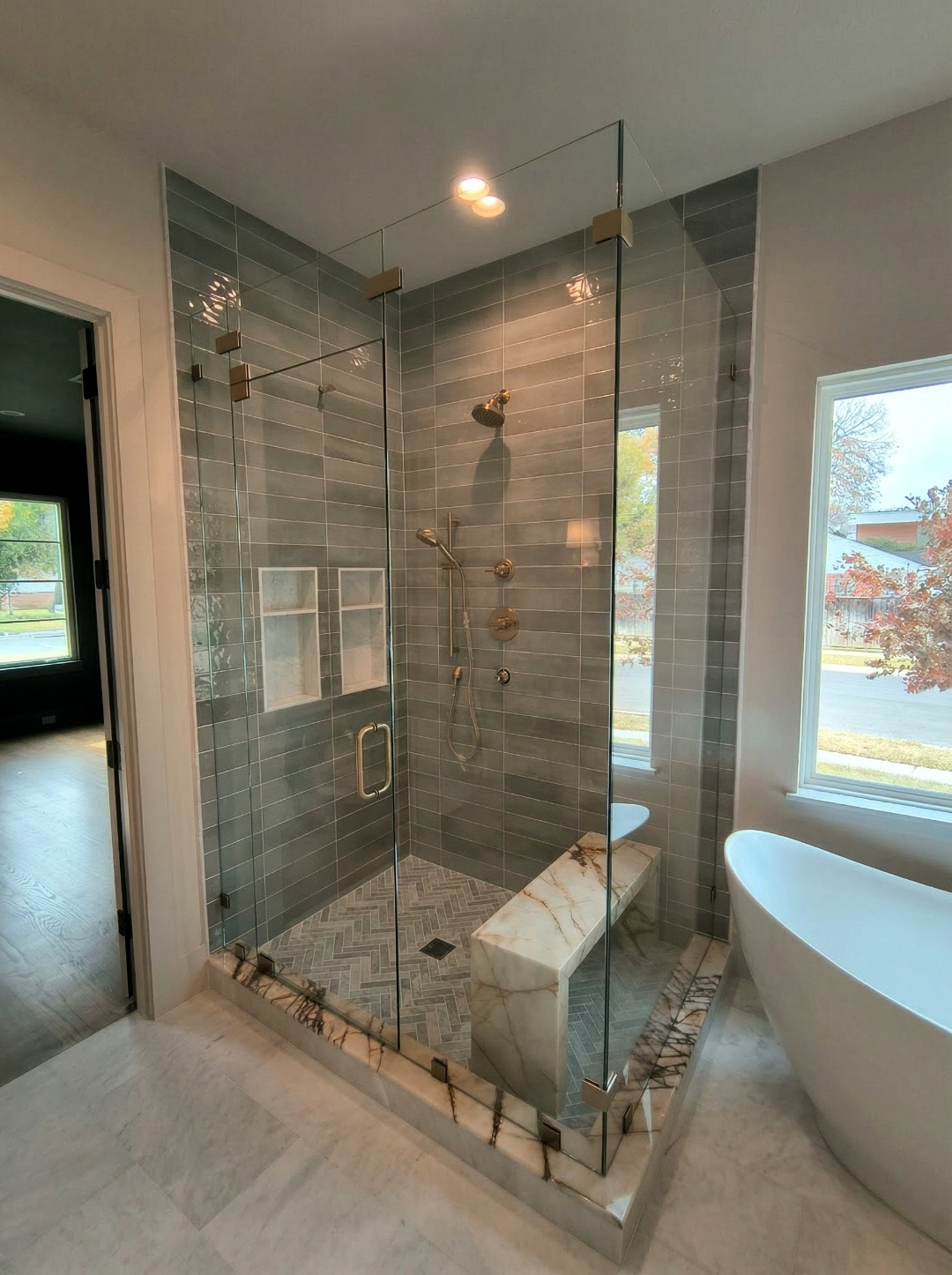 Modern corner shower with gray tile and frameless glass door